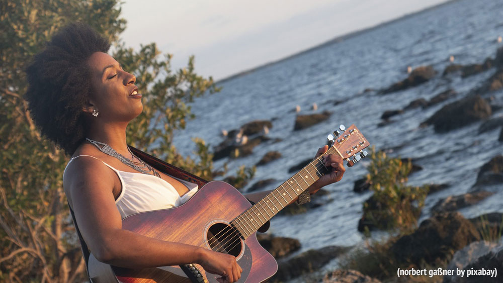 Frau mit Gitarre am Meer